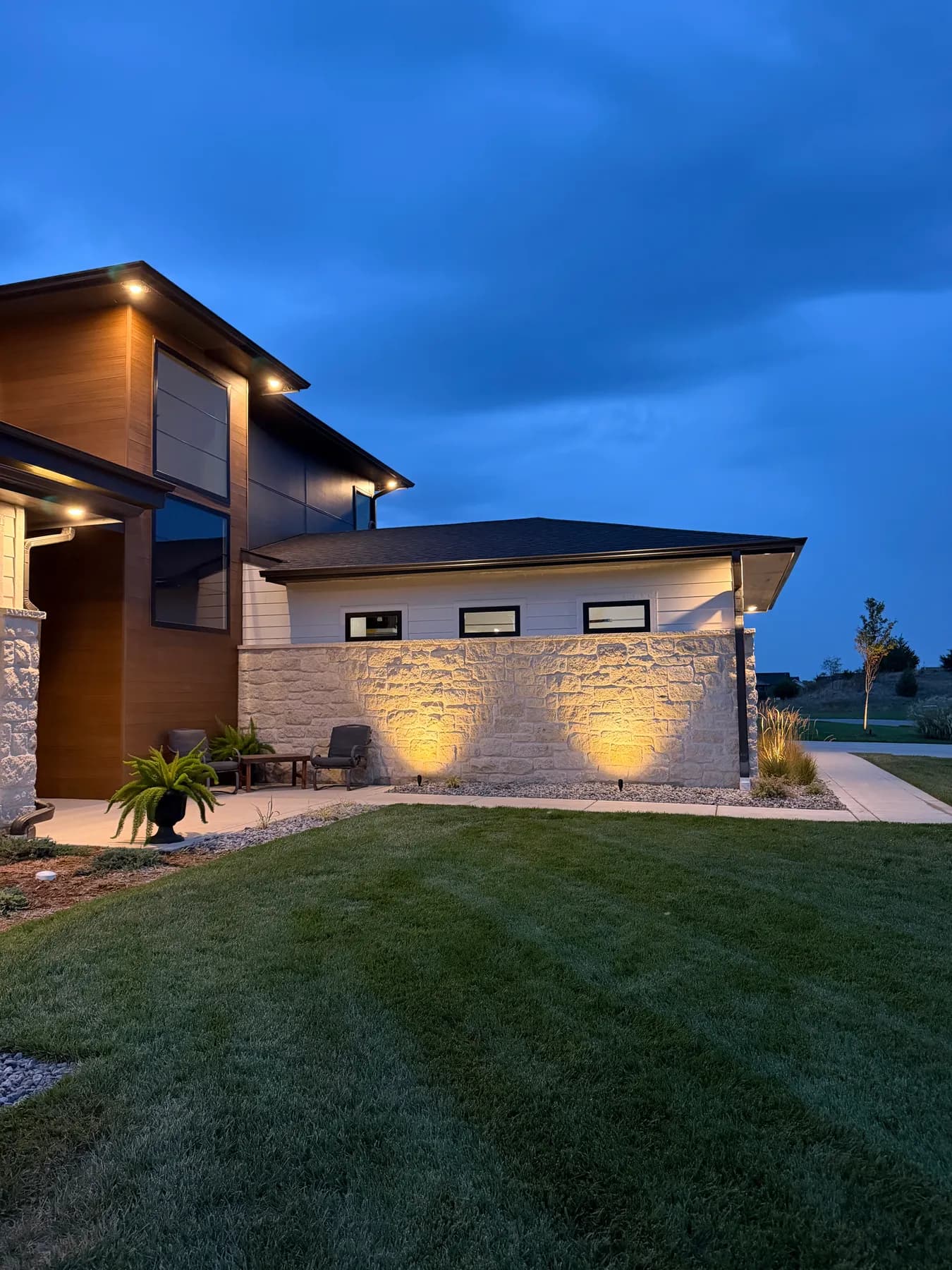 Uplighting grazing the stacked-stone wall of a modern home in the Coves