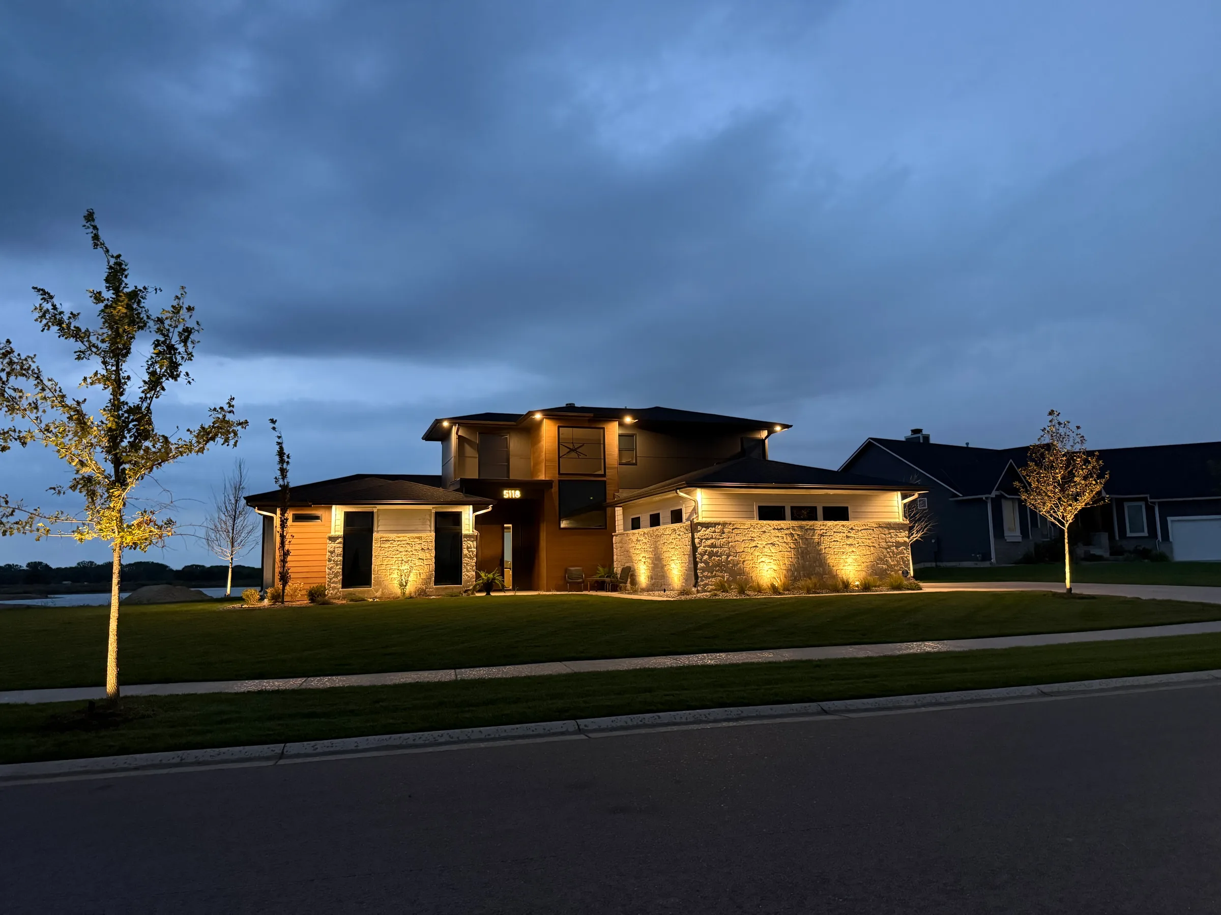 Modern Wichita home with architectural uplighting and tree lighting at dusk